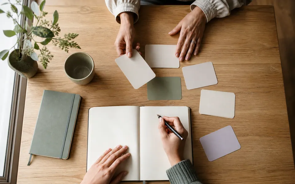 Manos escriben durante una actividad práctica con cuaderno y materiales.